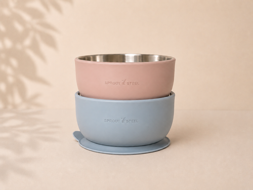 Brushed stainless steel baby toddler feeding bowl with silicone suction base in two colours, a blush pink (petal) and a light blue (mist)